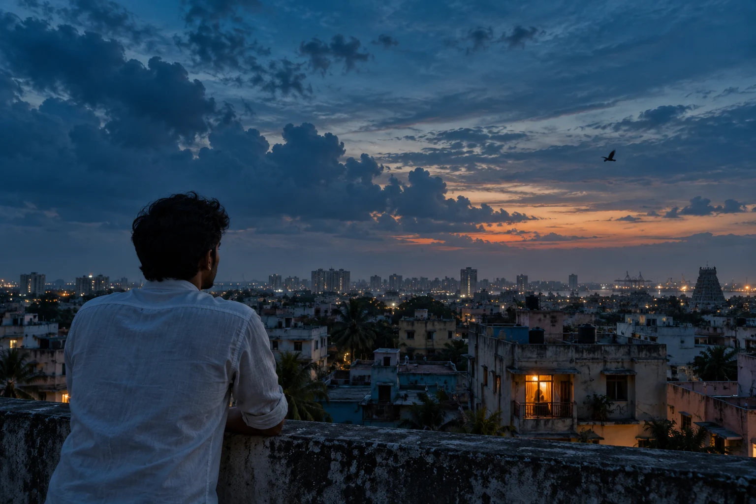 A young man on a rooftop looking out over the city at blue hour